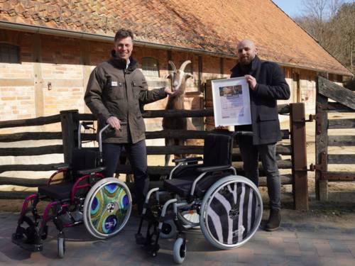 Zwei Männer stehen neben einem Rollstuhl, den mobilitätseingeschränkte Menschen im Erlebnis-Zoo ausleihen können.